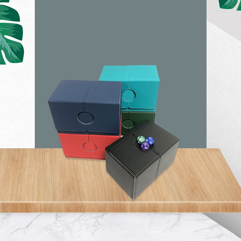 Four dice boxes in different colors stacked on a wooden surface with a gray background.